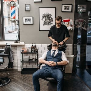 Barber working on a client's hair with precision in a stylish barbershop setting.
